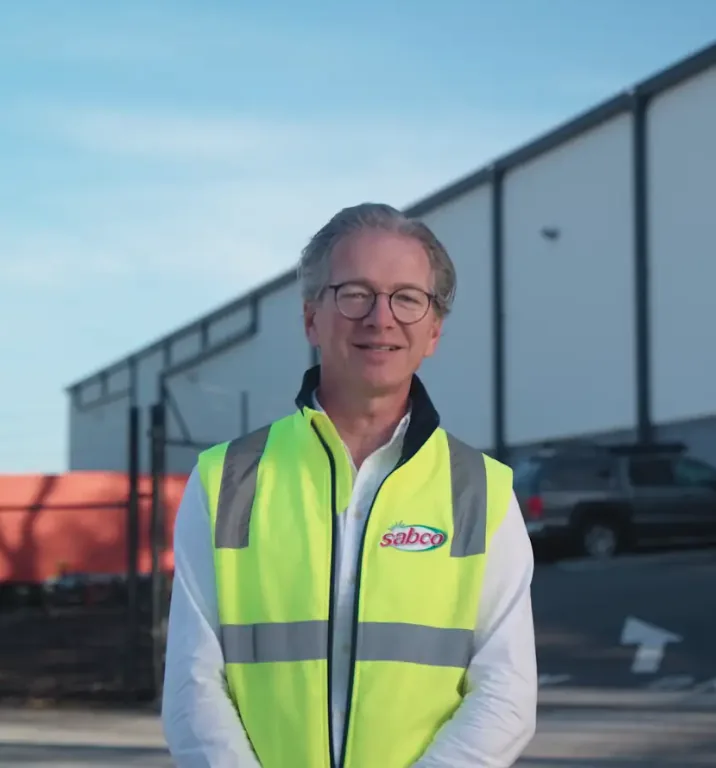 A man in a hi-vis Sabco vest standing in front of a warehouse.