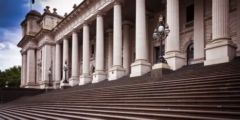 The columned front of a parliament building and its stone steps.