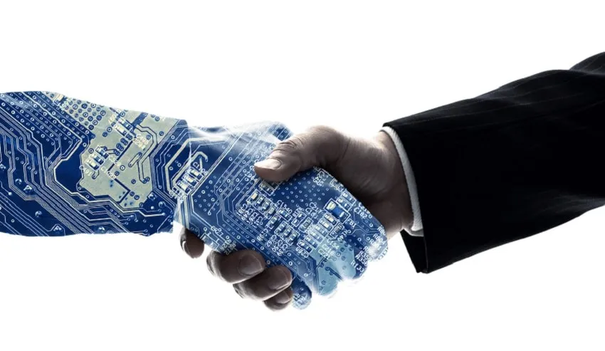 A handshake between a hand patterned with circuit boards and a human hand in a suit sleeve.