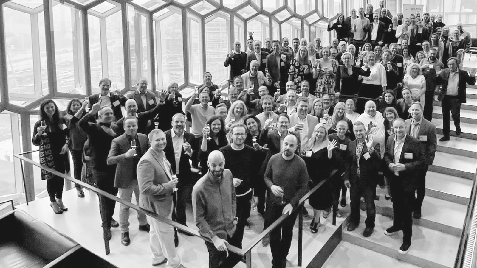 A large group of people pose together on a staircase in a black-and-white photo.