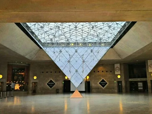 An upside-down glass pyramid hangs above a lobby floor, over a small pyramid below it.