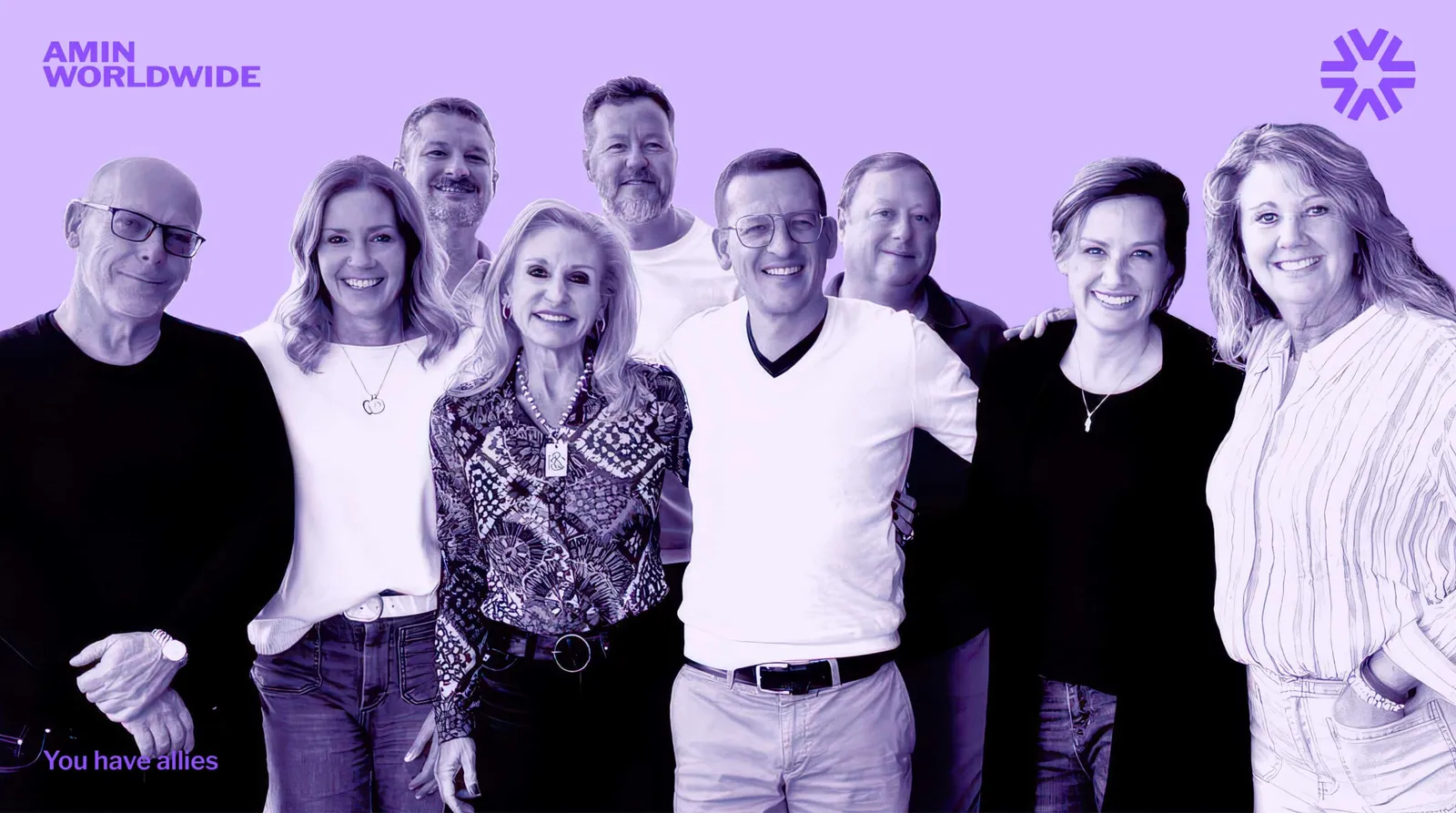 Nine people stand together, smiling, in a purple-tinted group photo.