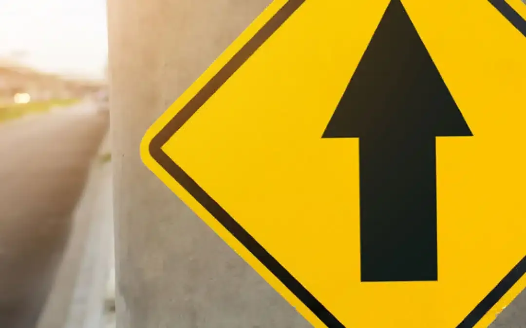 A yellow diamond road sign with a black arrow pointing up.