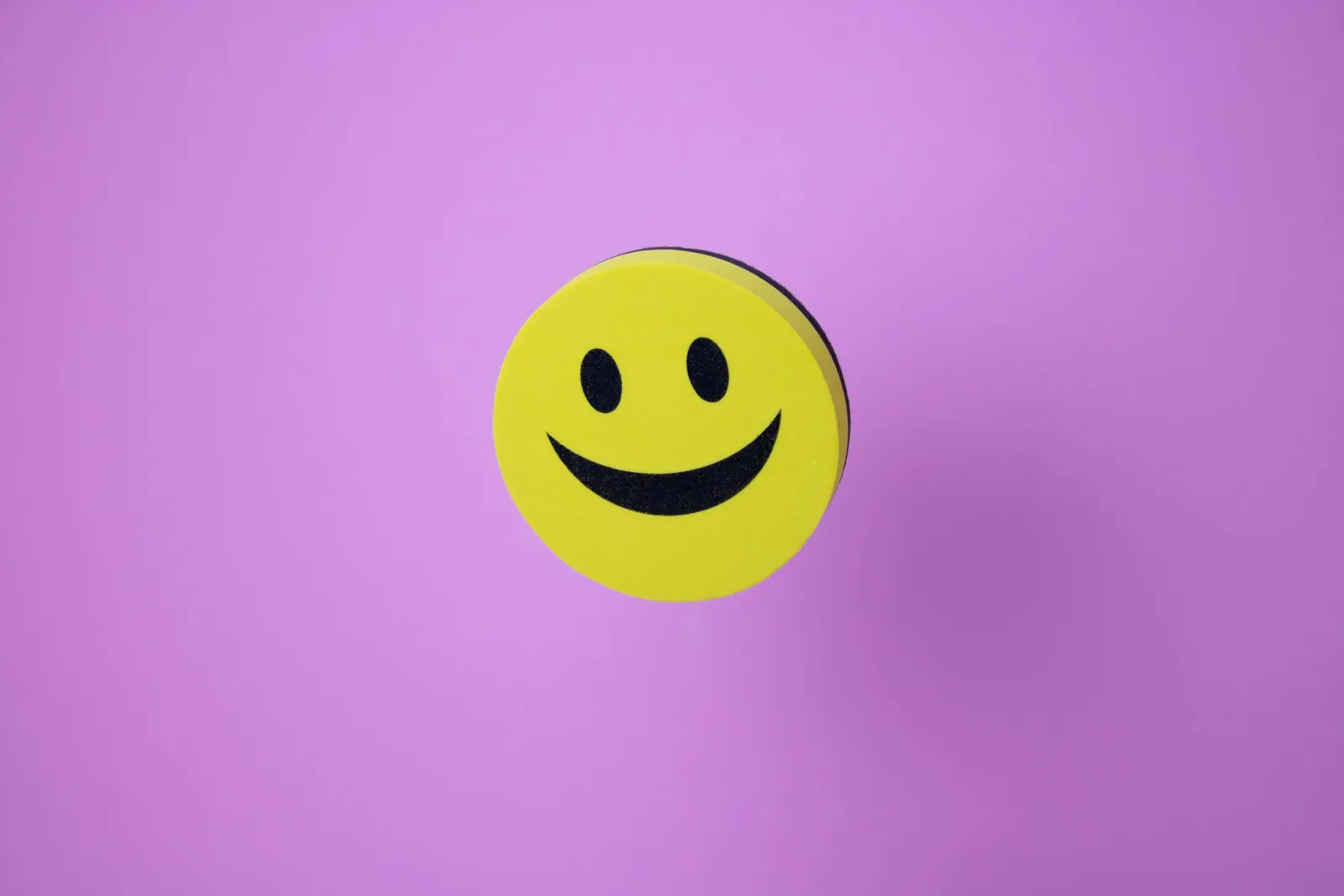 A yellow smiley face on a lilac background.