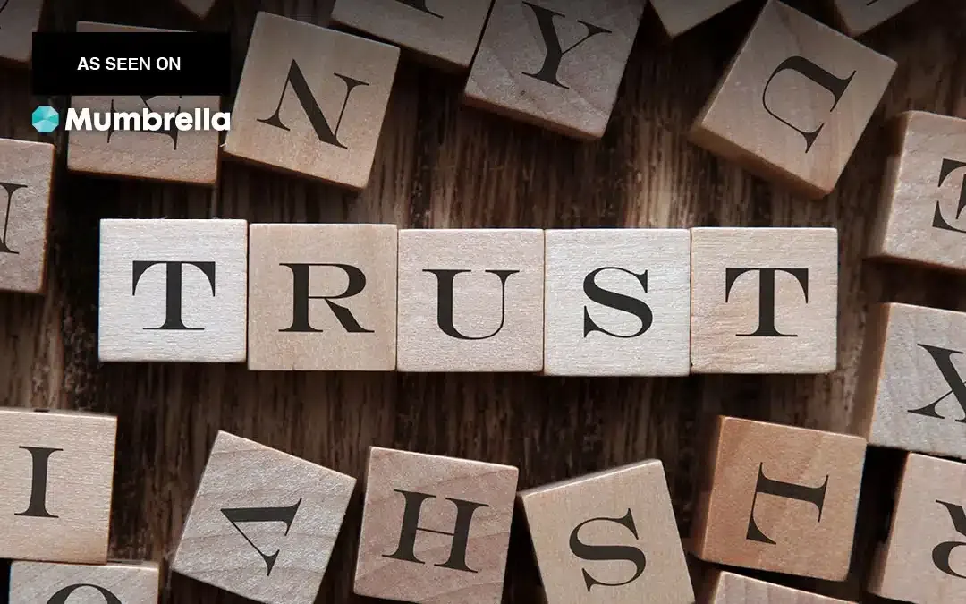 Wooden letter blocks spelling 'TRUST', with a Mumbrella 'As seen on' badge.